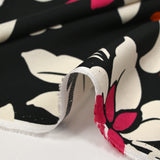 Fine viscose satin printed with fuchsia, orange and ecru royal flowers on a black background