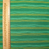 Sudadera de peluche a rayas amarillas y verde mar con fondo verde prado