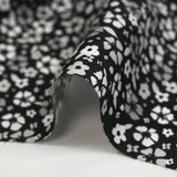 Viscose printed with myriad gray and white flowers on a black background