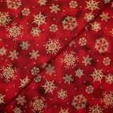 Cotton poplin printed with golden snowflakes on a red marbled background
