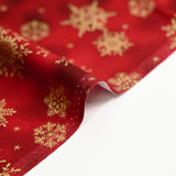 Cotton poplin printed with golden snowflakes on a red marbled background
