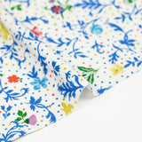Jersey de viscose satiné imprimé fleurs bleues fond confetti multicolore
