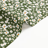 Viscosa estampada con flores blancas y amarillas, fondo caqui.
