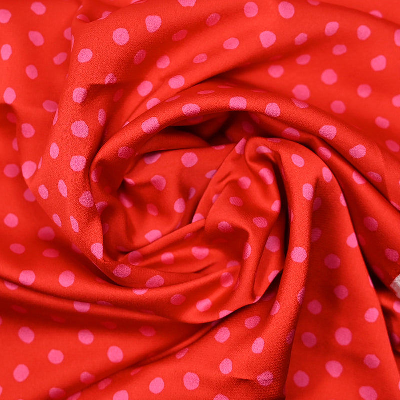 Crêpe satin polyester imprimé pois rose fond rouge