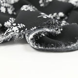 Crêpe satin polyester imprimé plantes blanc fond noir
