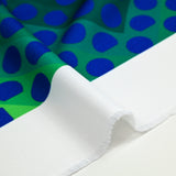 Gabardine de polyester imprimée gros pois bleu fond vert