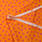 Crêpe satin de polyester imprimé à pois roses fond orange