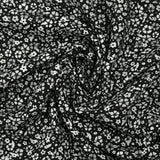 Viscose printed with myriad gray and white flowers on a black background
