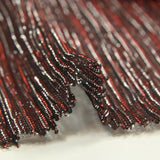 Malla fina de Lurex plisada en rojo y plata, fondo negro.