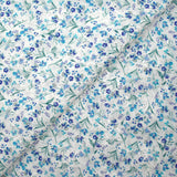 Bordado inglés estampado con pequeñas flores azules sobre fondo blanco.