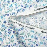 Bordado inglés estampado con pequeñas flores azules sobre fondo blanco.