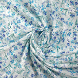 Bordado inglés estampado con pequeñas flores azules sobre fondo blanco.