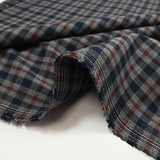 Tejido de polialgodón teñido con cuadros azul marino y burdeos oscuro sobre un fondo gris moteado.