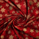 Cotton poplin printed with golden snowflakes on a red marbled background