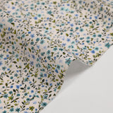 Voile de coton imprimé digital fleurettes bleues et feuillage vert sur fond écru