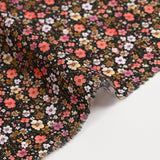 Prado de voile de algodón con estampado digital de pequeñas flores de color naranja y amarillo mantequilla sobre fondo negro
