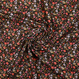Prado de voile de algodón con estampado digital de pequeñas flores de color naranja y amarillo mantequilla sobre fondo negro