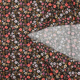Prado de voile de algodón con estampado digital de pequeñas flores de color naranja y amarillo mantequilla sobre fondo negro