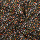 Prado de voile de algodón con estampado digital de pequeñas flores verdes y naranjas sobre fondo negro