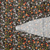 Prado de voile de algodón con estampado digital de pequeñas flores verdes y naranjas sobre fondo negro
