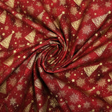Cotton poplin printed with golden fir trees on a red marbled background