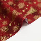 Cotton poplin printed with golden fir trees on a red marbled background