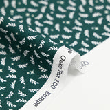 Cotton poplin printed with white twigs and stars on a green background